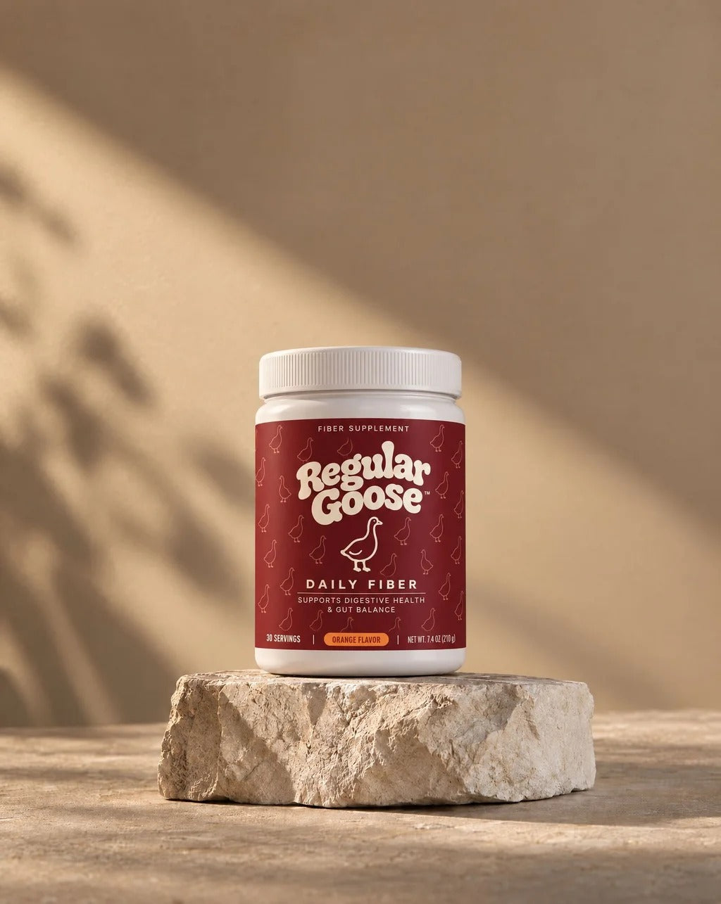 A jar of Regular Goose Daily Fiber on a stone pedestal with warm afternoon light and shadow